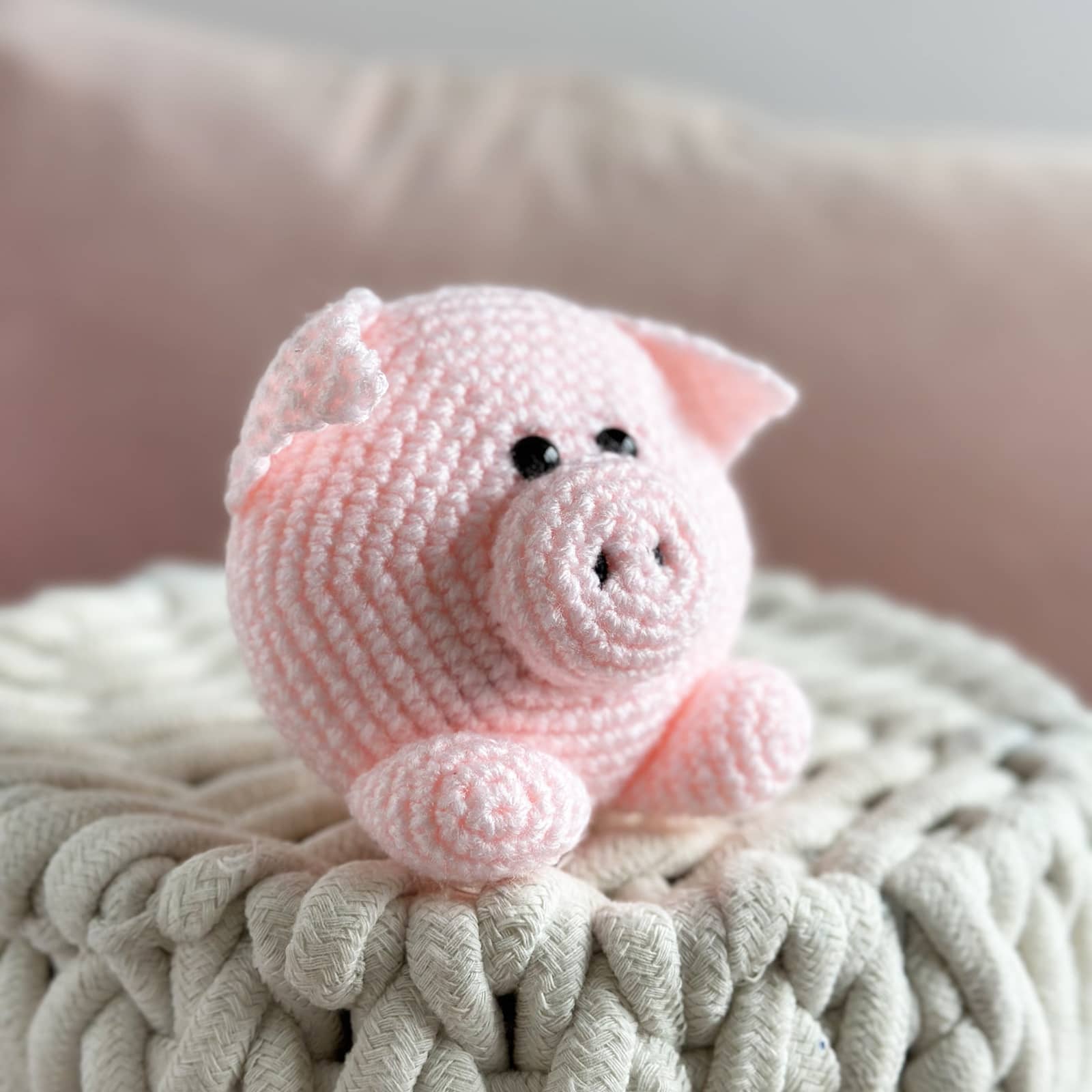 Pink crochet pig toy on a textured surface with a blurred background