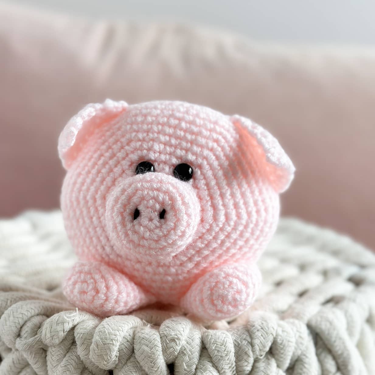Pink crochet pig toy on a textured surface with a blurred background