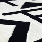 close up of black and white modern art abstract crochet blanket on table
