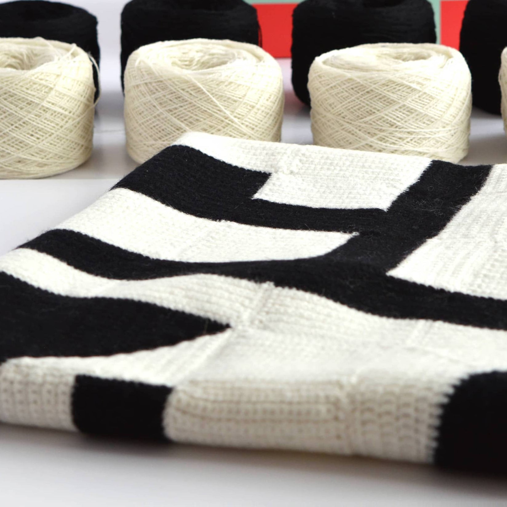 modern art abstract design crochet blanket kit showing contents including yarn and box on table