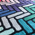 close up of granny square blanket using rectangles in blue green and purples