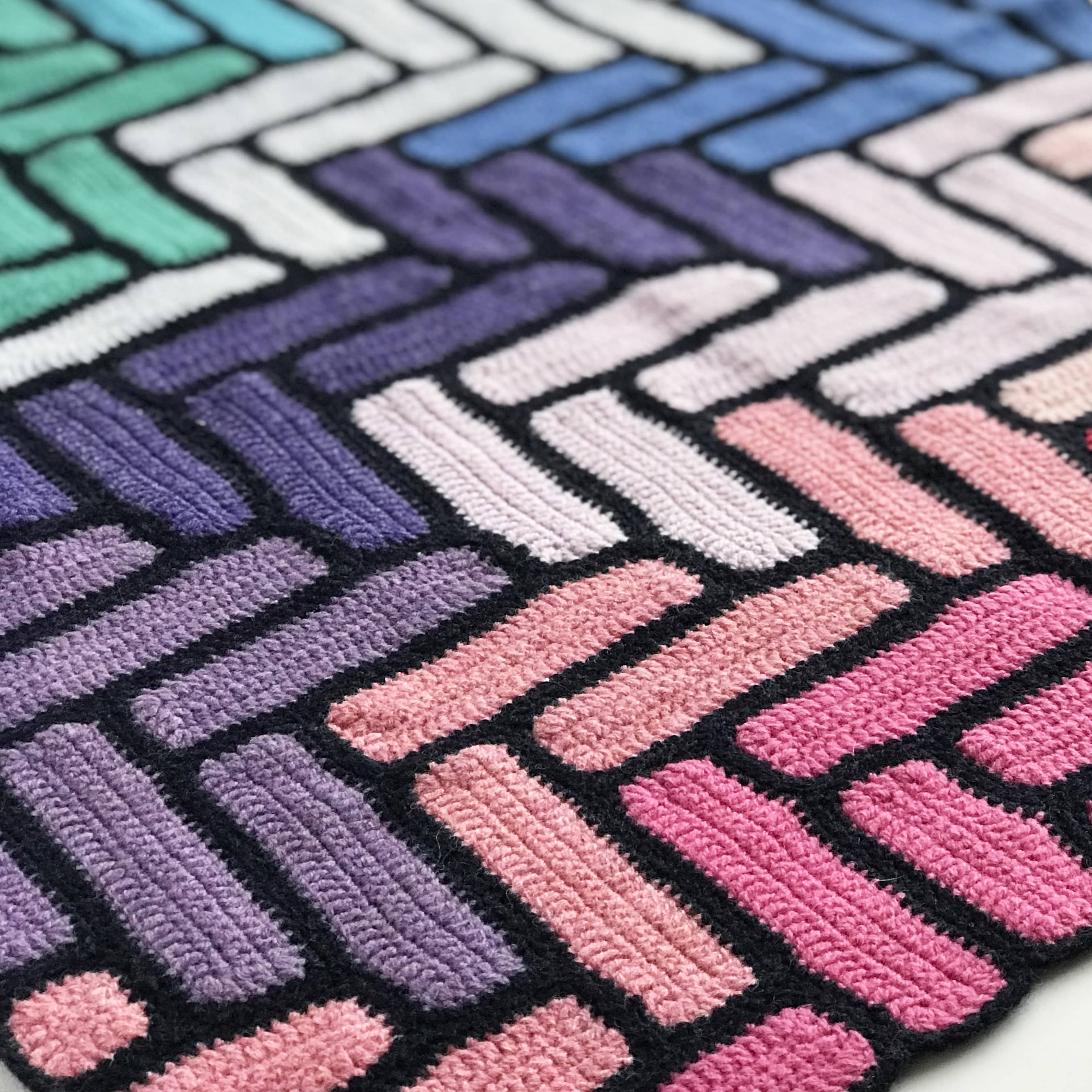 close up of bright modern crochet blanket showing pinks and purples