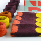 granny square crochet kit in mid century modern design showing contents on kit laid out on table with yarn and box