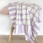 granny square blanket in lilac and white pastel colours on stool