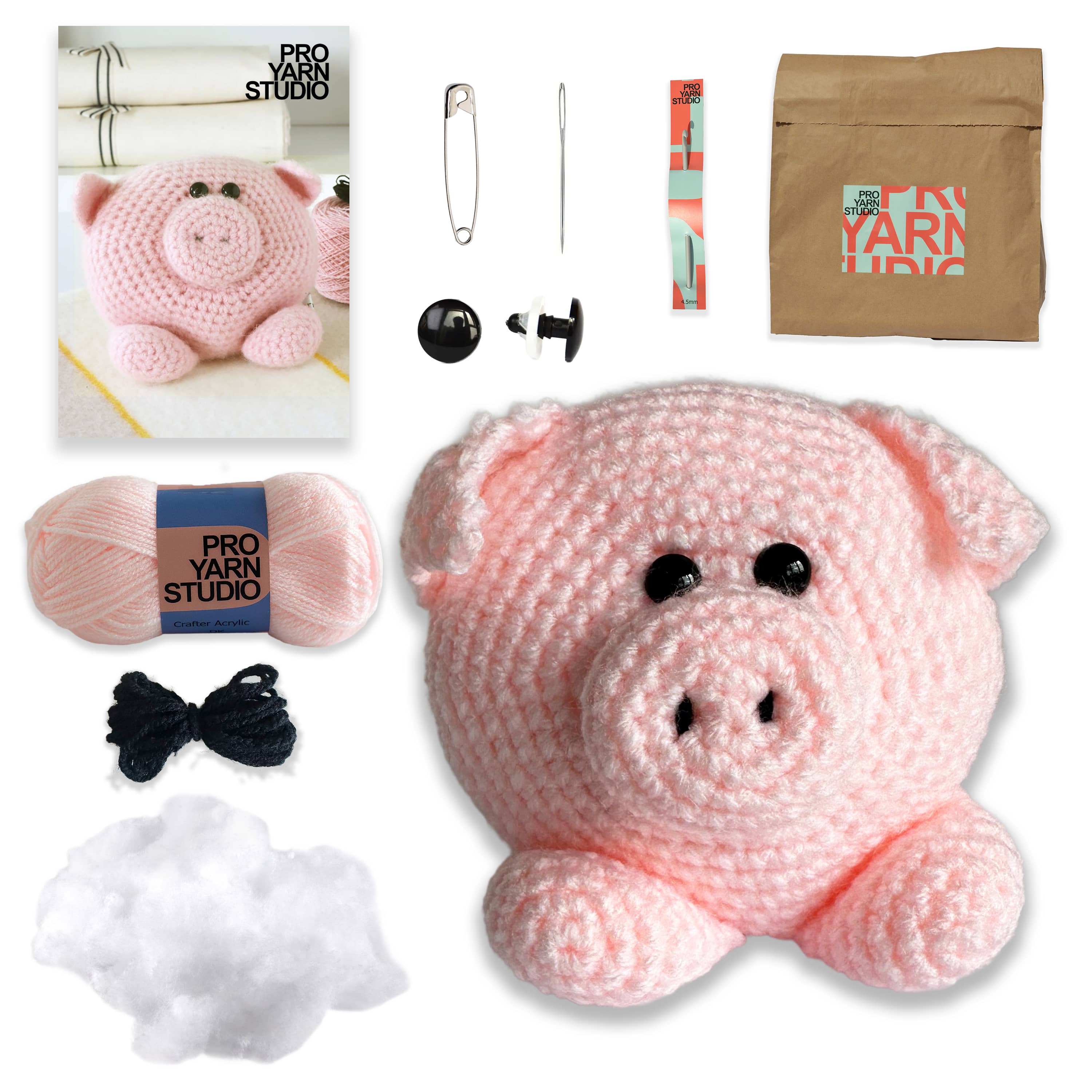 Pink crochet pig with yarn, needles, and other crafting supplies on a white background