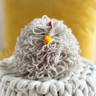 Close-up of a textured white yarn ball with a small yellow ball on a yellow background