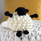 Handmade crochet sheep toy on a textured surface with a blurred background