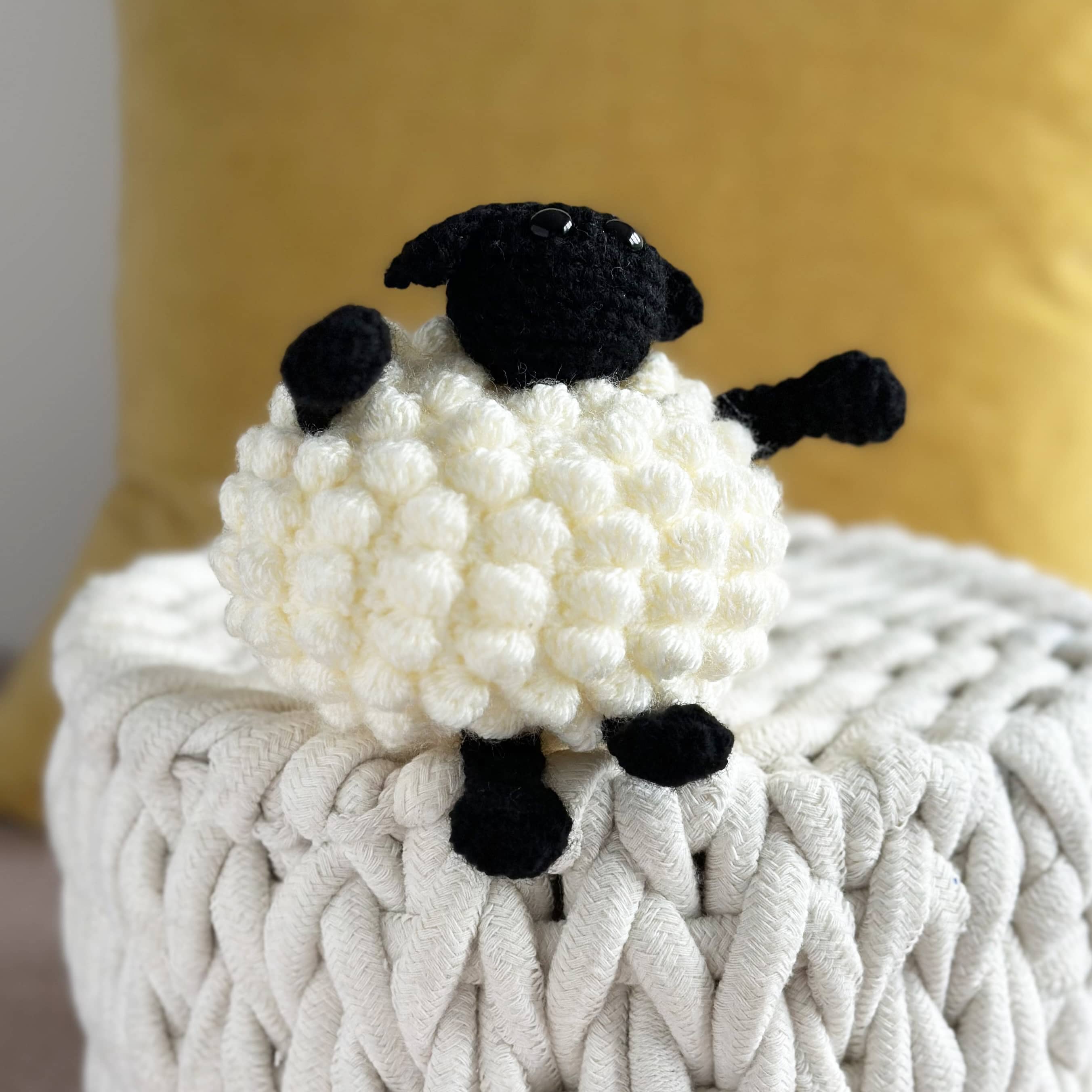 Crocheted sheep toy on a textured surface with a blurred background