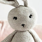 Close-up of a crocheted gray bunny toy with a blurred background
