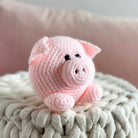 Pink crochet pig toy on a textured surface with a blurred background