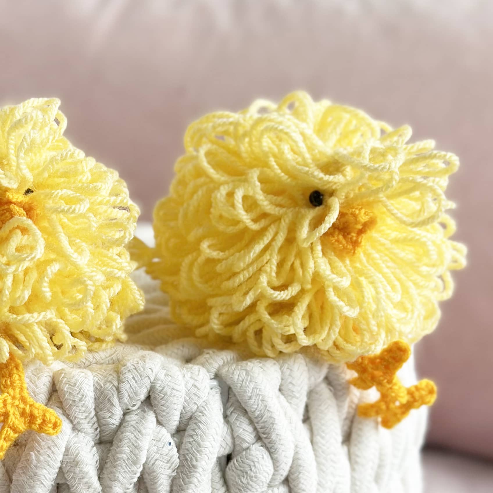 Two yellow lion plush toys with a white blanket on a light pink background