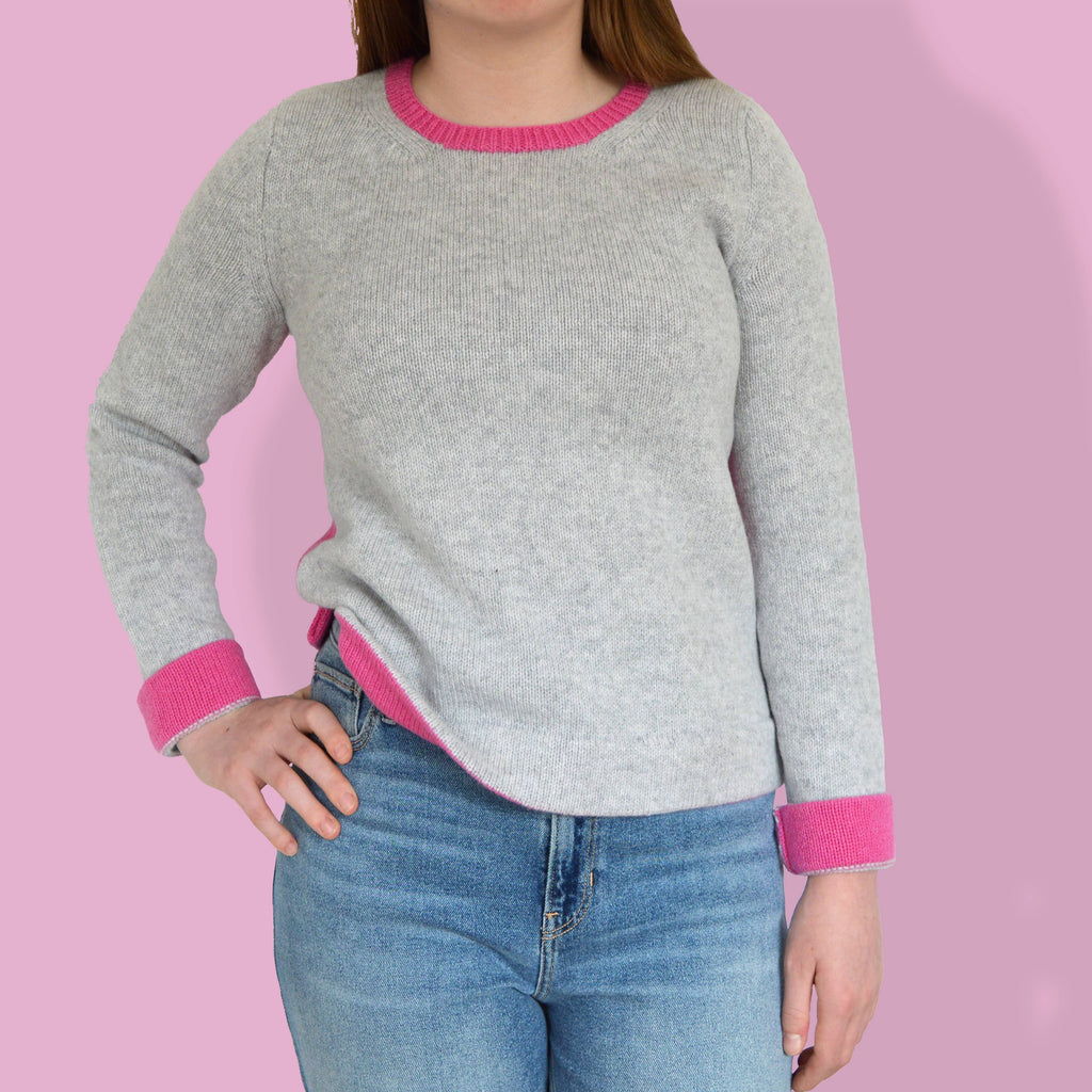 woman wearing modern knitting pattern jumper, knitting kit.  grey marl yarn and bright pink sweater knitting pattern