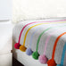 pom pom and stripe crochet blanket kit on bed